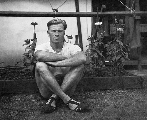 Julius Antoniak sitting cross-legged in front of a flower bed at the door of a wooden-floored canvas temporary accommodation tent at Clyde Migrant Camp, Sydney, Australia in 1949. Julius Antoniak sitting cross-legged in front of a flower bed at the door of a wooden-floored canvas temporary accommodation tent at Clyde Migrant Camp, Sydney, Australia in 1949.